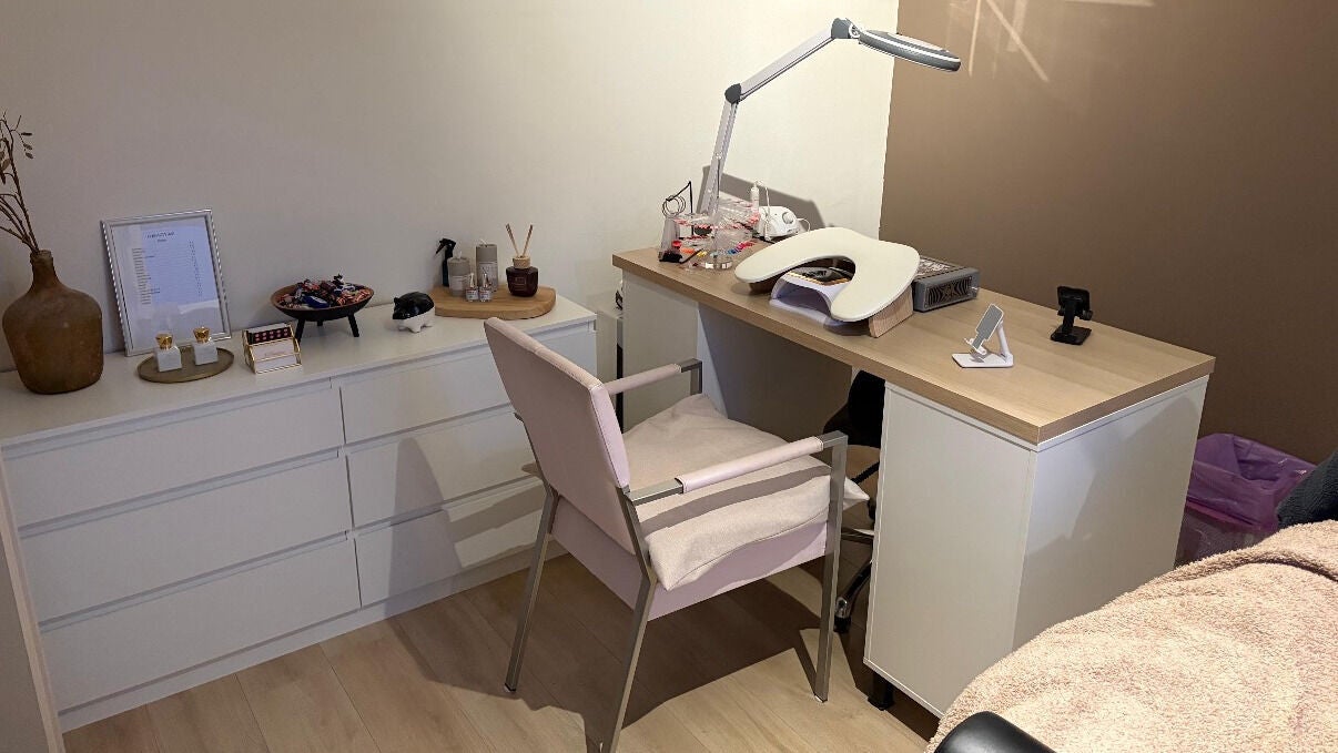 De witte nageltafel met lamp en de roze stoel in de salon